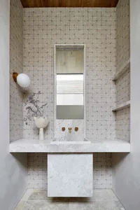 A modern bathroom with marble tiles, a floating sink, and geometric wall tiles.