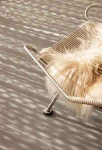 A modern metal frame rope seat with a plush, beige, fur-like cushion.
