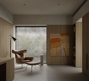 A modern minimalist living room featuring a wooden armchair, ottoman, and floor lamp.