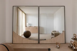 A minimalist interior with large mirrors and wooden elements.