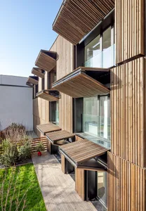 Modern residential building with wooden balconies and glass windows.