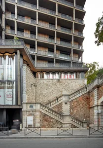 A modern residential building made of concrete with glass windows and a metal railing.