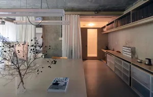 Minimalist office interior with concrete walls, wooden furniture, and white curtains.
