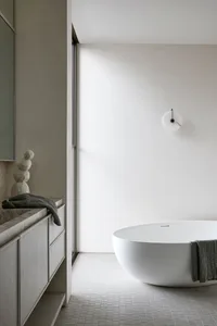 A minimalist bathroom with a ceramic bathtub, marble countertop, and metallic accents.