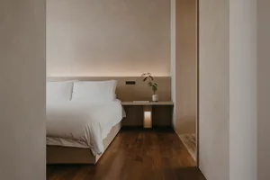 A minimalist bedroom featuring a wooden bed frame and flooring.