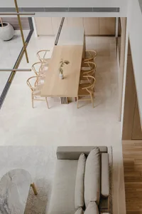 A minimalist dining room featuring a wooden table with six chairs and a small plant centerpiece.