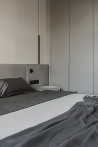 A modern bedroom featuring gray upholstered furniture and fabric materials.