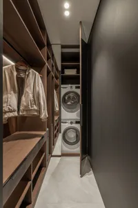 Modern closet laundry room with wooden shelves and a stacked washer and dryer.