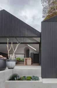 A modern minimalist house with a concrete exterior, featuring a geometric design and an overhanging roof.