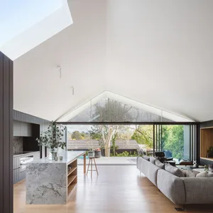 Modern house interior with marble kitchen island, concrete ceiling, and wooden floor.