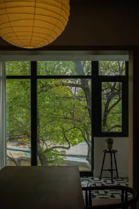 A modern dining room featuring a wooden table with a large window overlooking green trees.