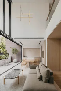 A modern living and dining room featuring glass, metal, and wooden elements.