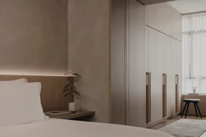 A modern minimalist bedroom with a wooden bed frame, a wooden headboard, and wooden furniture.