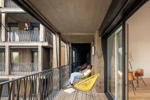 Modern residential balcony featuring wood flooring and black metal railings.
