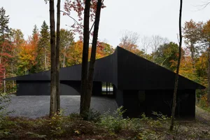 The exterior of a modern house featuring black aluminum cladding and large windows.
