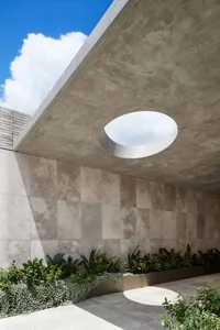 Modern building exterior featuring circular window and concrete materials.