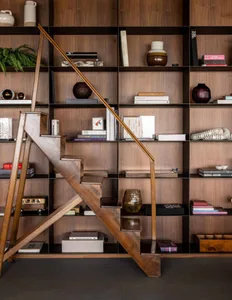 A modern interior design featuring a bookshelf filled with various books and decorative items, with a wooden staircase in the