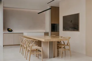 A modern minimalist kitchen with wooden furniture and a white backsplash, featuring a wooden table and wooden chairs.