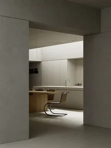 Minimalist kitchen featuring concrete countertops and wooden dining table.