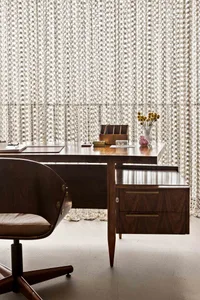 A modern office setting featuring a wooden desk with a leather chair, a vase with flowers, and various office supplies.