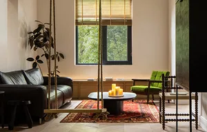 Industrial-style living room featuring wooden furniture, a coffee table with candles, and large windows with greenery outside