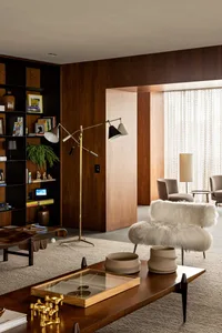 Modern living room featuring a wooden floor, fabric chairs, ceramic vases, and brass floor lamp.