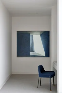 A minimalist office space featuring a large blue painting on the wall with a geometric design.