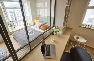 A minimalist bedroom featuring wood furniture, glass walls, and fabric bedding.