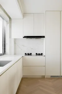 Modern, minimalist kitchen with white marble countertops and wooden flooring.