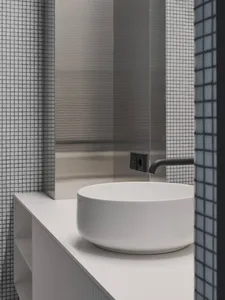 A modern bathroom with a round white ceramic sink and a minimalist design.