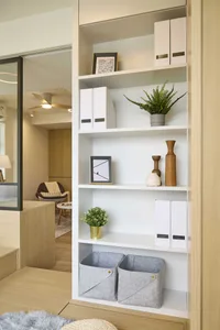 A modern living room with minimalist design featuring light wood flooring, white shelves with various decor items, and green 