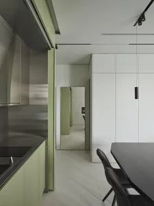 Modern minimalist kitchen with stainless steel appliances, green cabinetry, and white countertops.