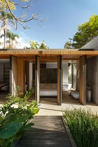 A minimalist residential interior with an open-concept layout, featuring wood accents and a connection to a garden.