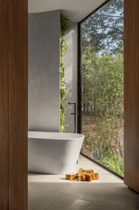 Modern bathroom interior featuring a freestanding bathtub, concrete walls, and large windows with natural light.