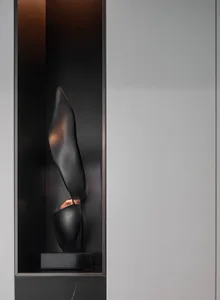 A modern black metal sculpture with an abstract, abstracted shape, placed within a recessed niche.