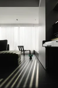 A modern living room with glass walls, a leather sofa, and a steel chair.