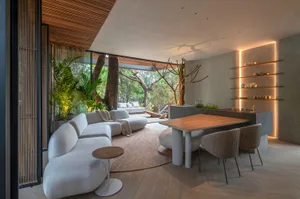 Modern living room with a wooden table, upholstered furniture, and glass windows.