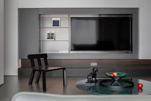 A modern living room featuring a metallic black dining chair on a polished concrete floor against a metallic black wall.