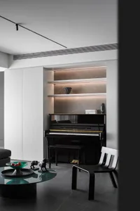 A modern living room featuring a black piano with metallic accents and a marble wall backdrop.