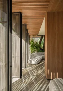 A modern living room with wooden walls and white furniture, featuring a large white sofa and green plants.