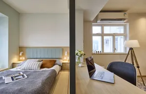 A modern minimalist bedroom featuring a wooden bed frame, wall-mounted lights, and a window with a view.