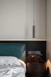 Modern minimalist bedroom featuring a wooden bed with a teal headboard and a metallic pendant light fixture.