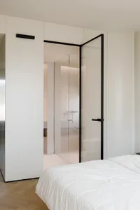 Modern bedroom with a glass door, white walls, and minimalist design.