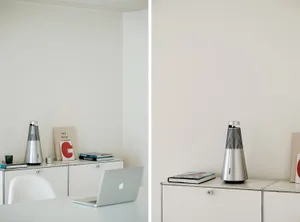 A minimalist white interior featuring a metal audio speaker on a white cabinet.