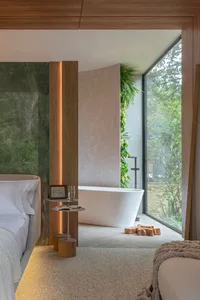 A minimalist bedroom with a marble wall, wooden accents, and a large window overlooking trees.