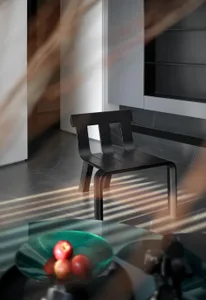 A modern minimalist interior featuring a black wooden chair with a sleek, curved design.