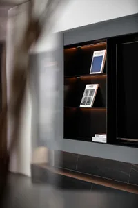 A modern bookshelf with dark wood and glass shelves displaying books.