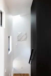 Minimalist staircase with concrete steps, white walls, and a black door.