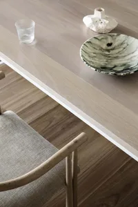 Modern dining room featuring a wooden table with a vase and a marble bowl.