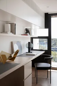 A modern minimalist office desk space with a wooden desk, metal chair, and glass lamp.